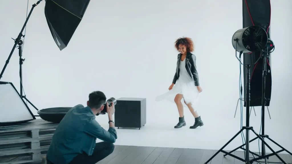 Fotograf fotografiert Frau bei einer Studioaufnahme mit professioneller Beleuchtung – Arbeiten am Set Fotograf fotografiert Frau bei einer Studioaufnahme mit professioneller Beleuchtung – Arbeiten am Set