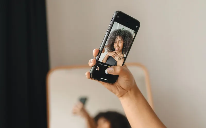 Žena se usmívá při pořizování selfie chytrým telefonem v interiéru – jak chránit dosah na Instagramu